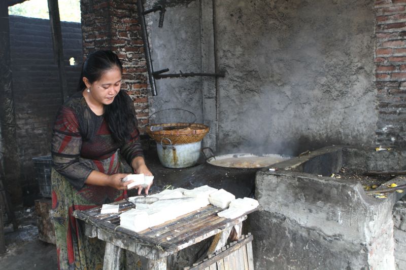 A woman fries tofu using plastic waste as a fuel