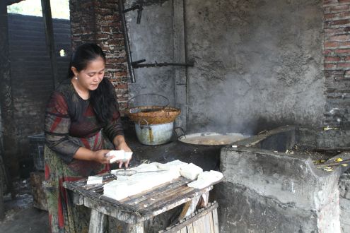 A woman fries tofu using plastic waste as a fuel 