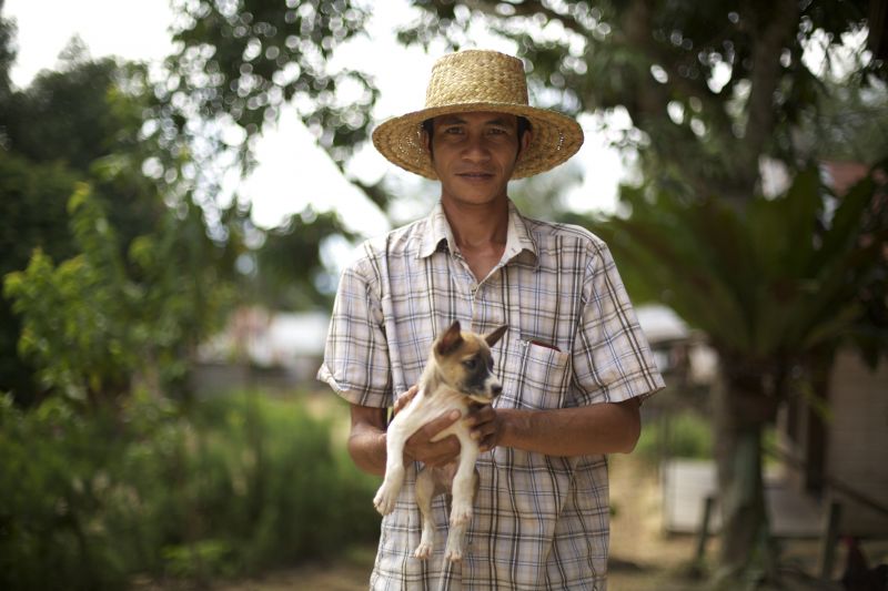 Pa Yusep posing for the camera while holding a puppy
