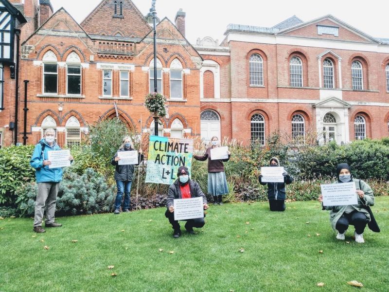 People stand socially distanced holding signs demanding climate action