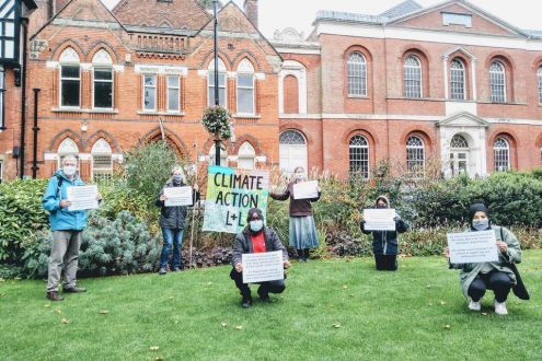 People stand socially distanced holding signs demanding climate action