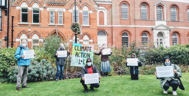 People stand socially distanced holding signs demanding climate action