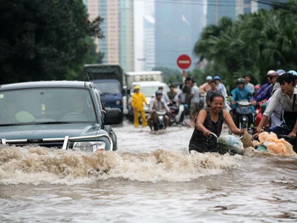 Cyclists struggle to push their bikes through the floodwater in Hanoi, China