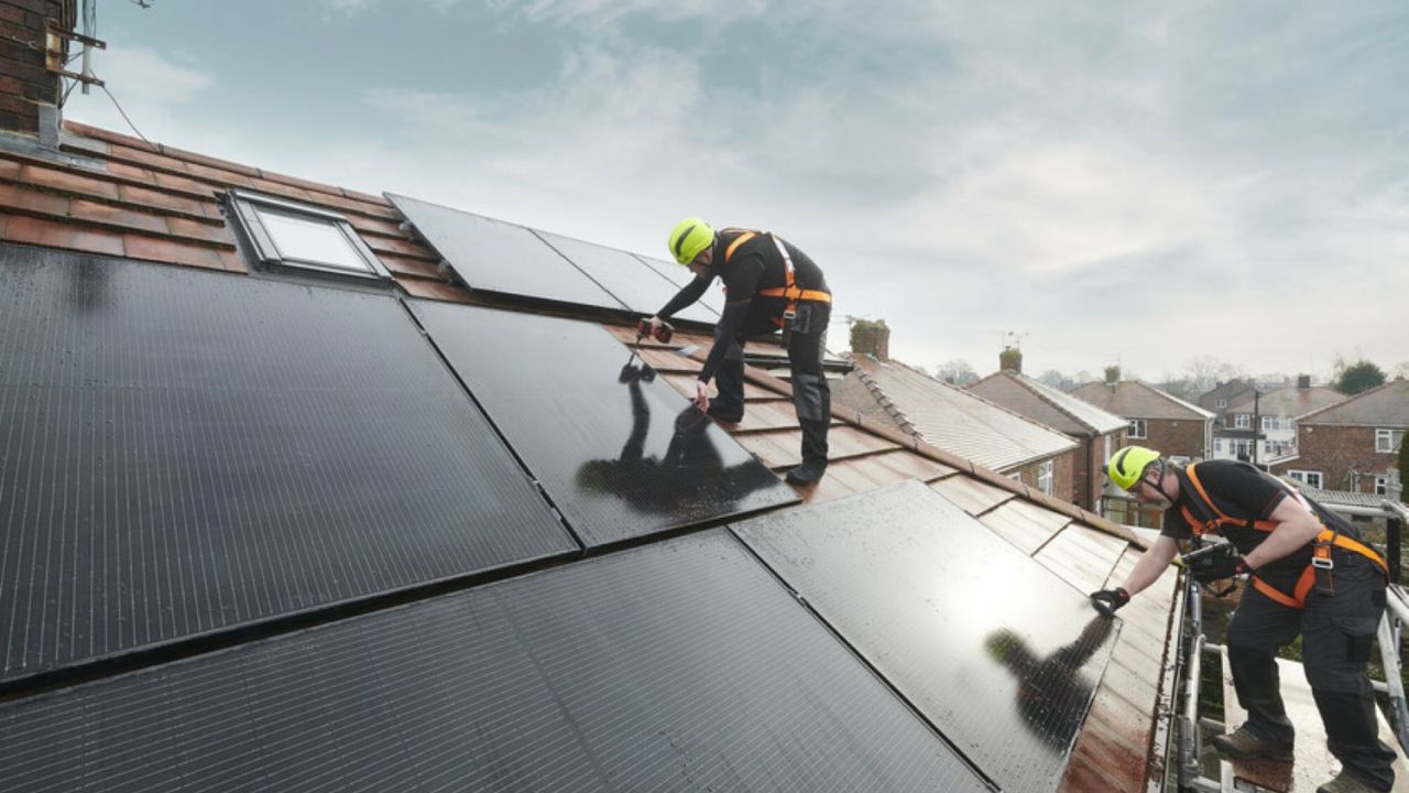 Two men installing solar panels on a home