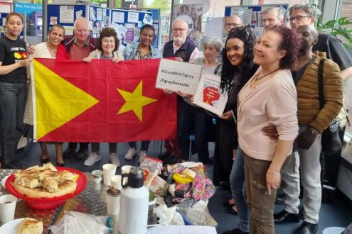 A group photo of people holding a Tigray flag and signs which read #StandWithTigray