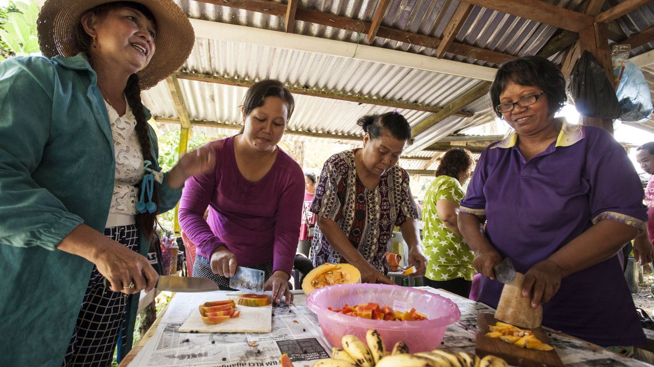 Women, happy, preparing fruit together in a wooden hut