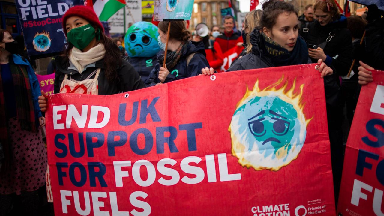 Women holding a banner 'End UK support for fossil fuels' in a protest march