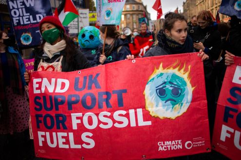 Women holding a banner 'End UK support for fossil fuels' in a protest march