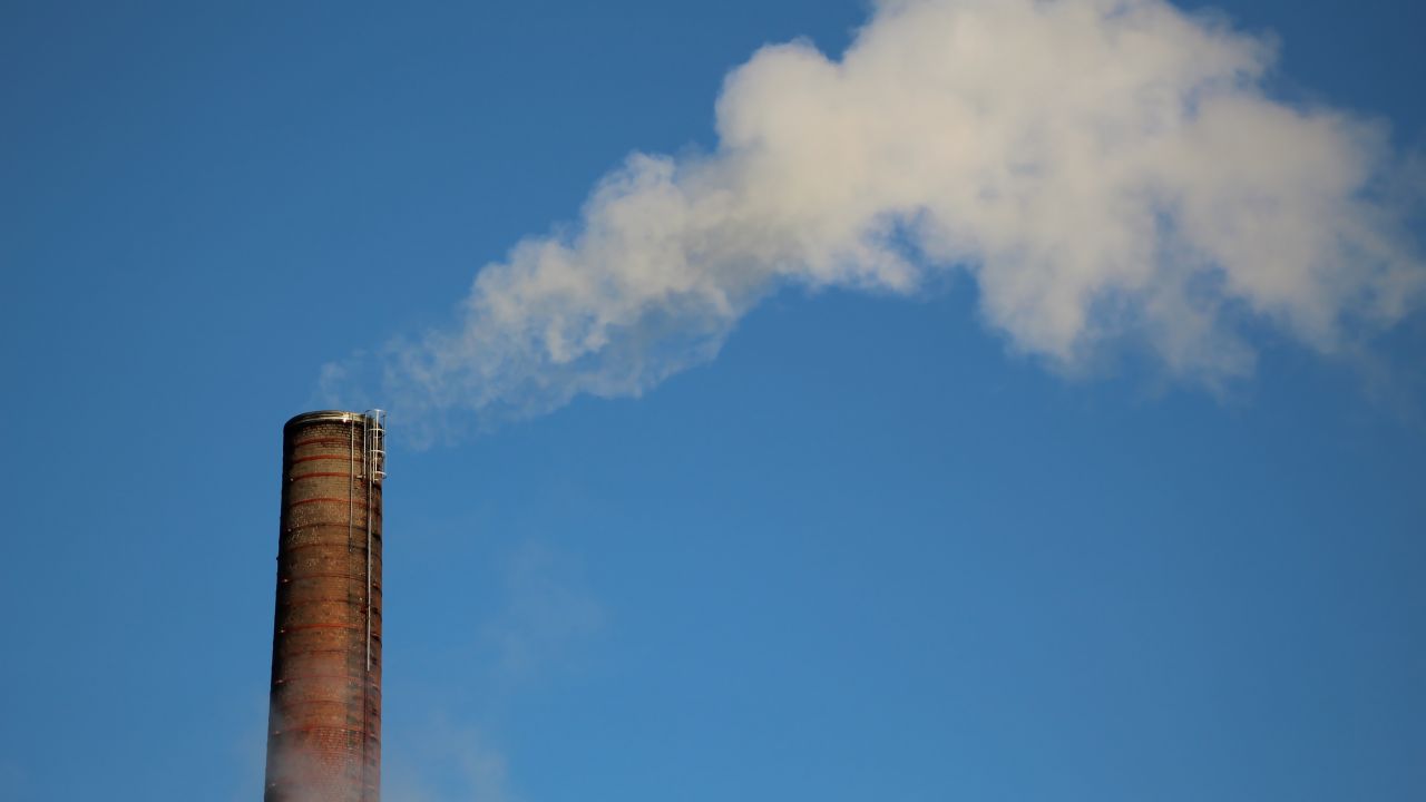 Factory emitting smoke amongst clear sky