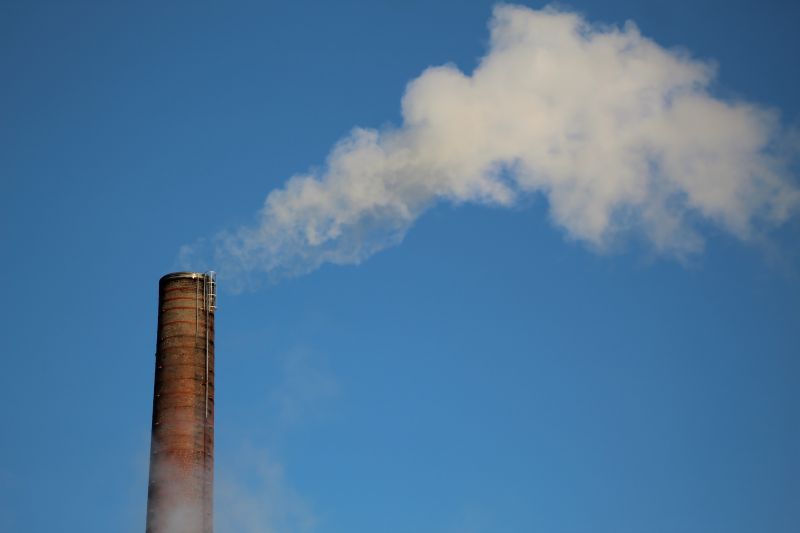 Factory emitting smoke amongst clear sky