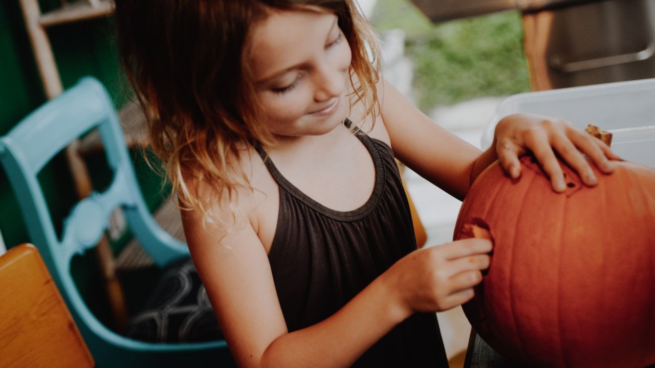 Young girl carving pumpkin