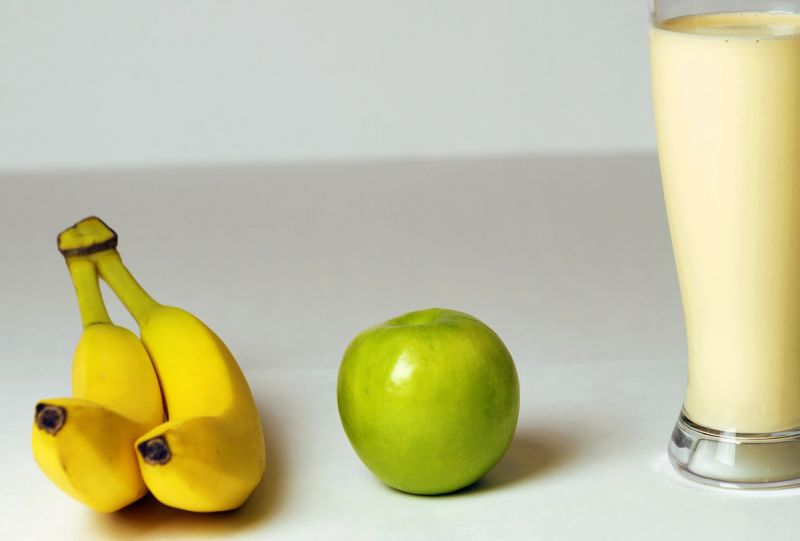 Yellow bananas, green apple and glass of milky smoothie