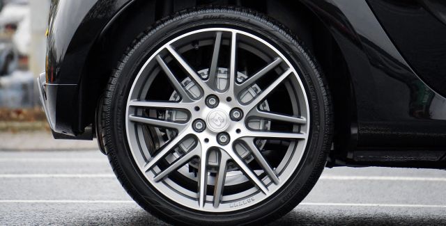 A close up of a tyre on the back wheel of a black car