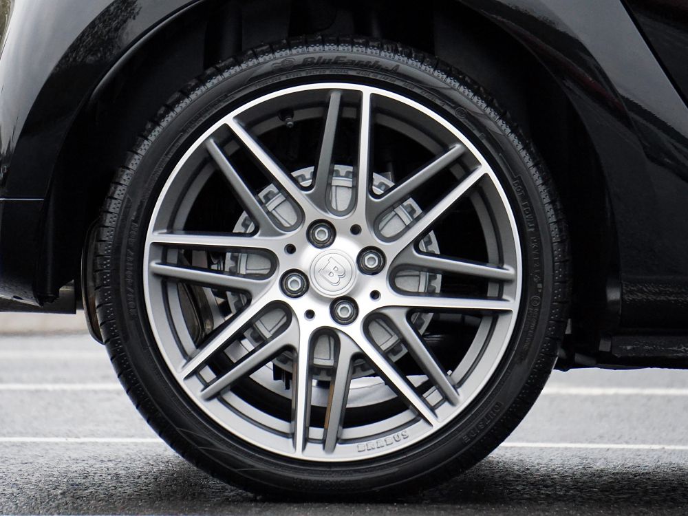 A close up of a tyre on the back wheel of a black car