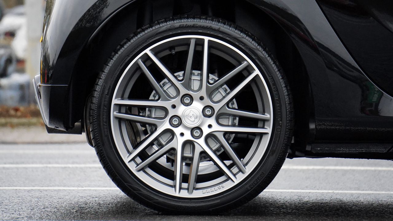 A close up of a tyre on the back wheel of a black car