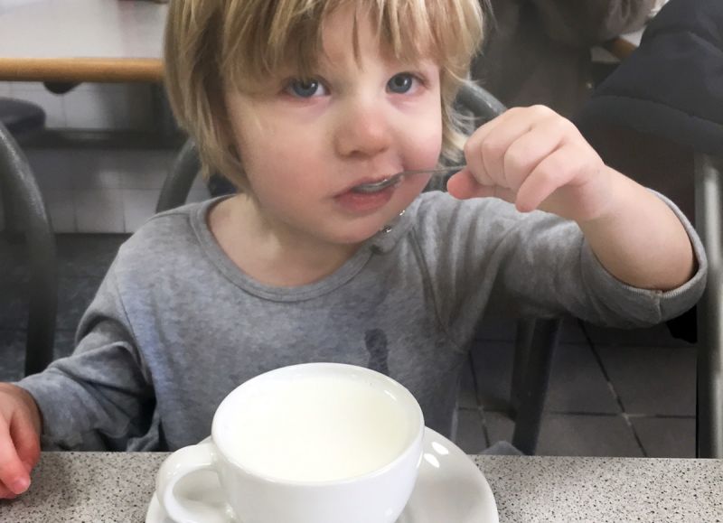 Small boy with metal spoon and ceramic cup