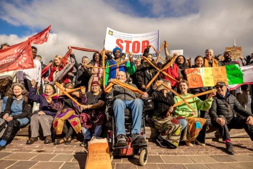 A group of people holding divestment banners and orange crosses made of tied fabric