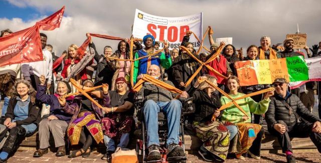 A group of people holding divestment banners and orange crosses made of tied fabric