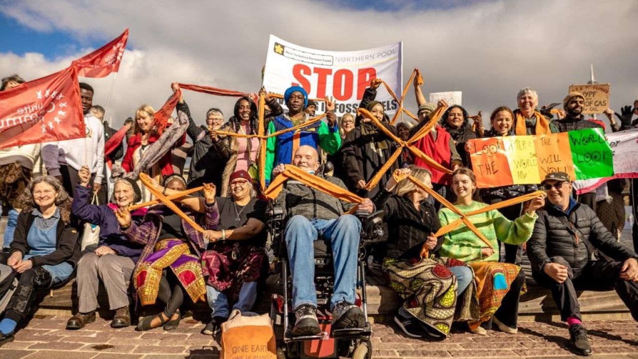 A group of people holding divestment banners and orange crosses made of tied fabric