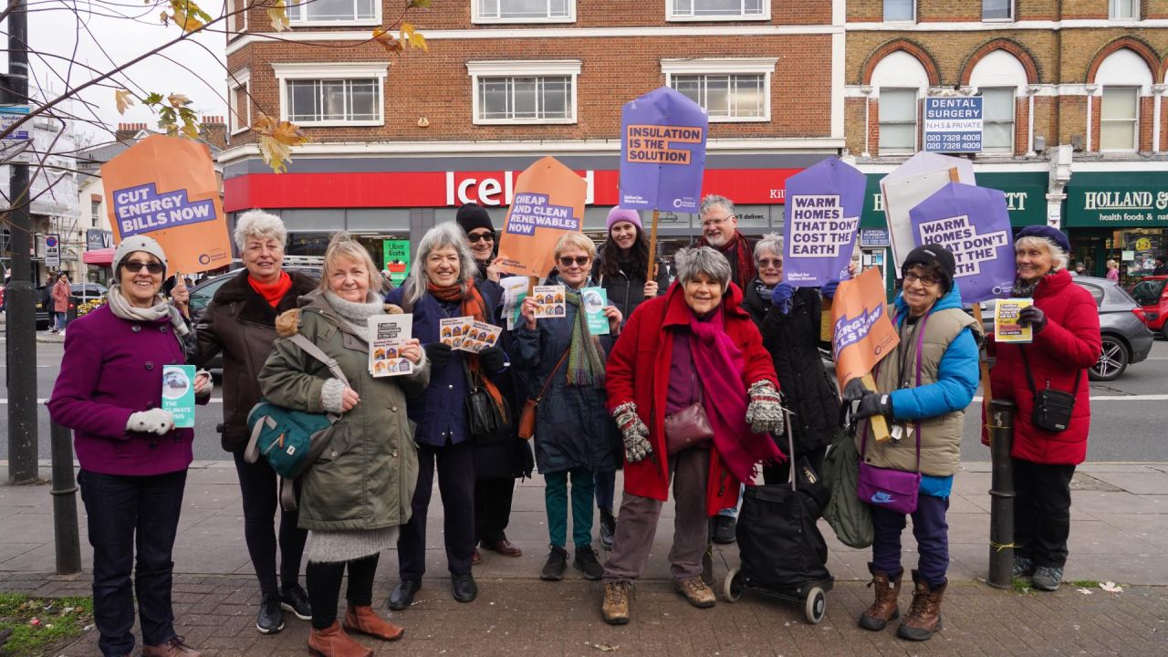 A group of campaigners stand together on a street holding placards