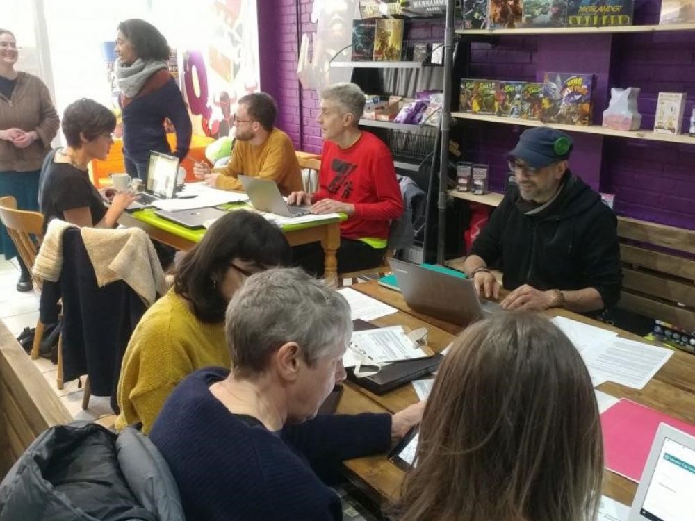 Members of a local action group sit at a table with laptops talking