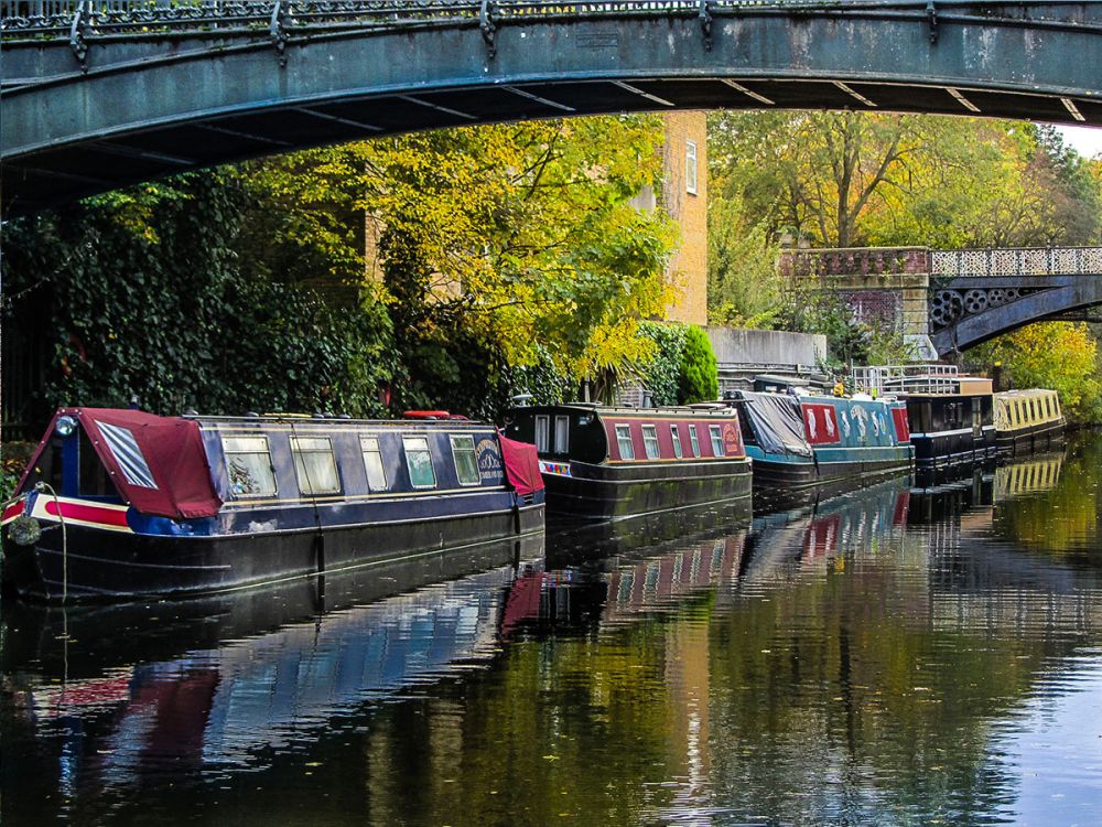 Houseboats moored on the bank of a canal under a bridge