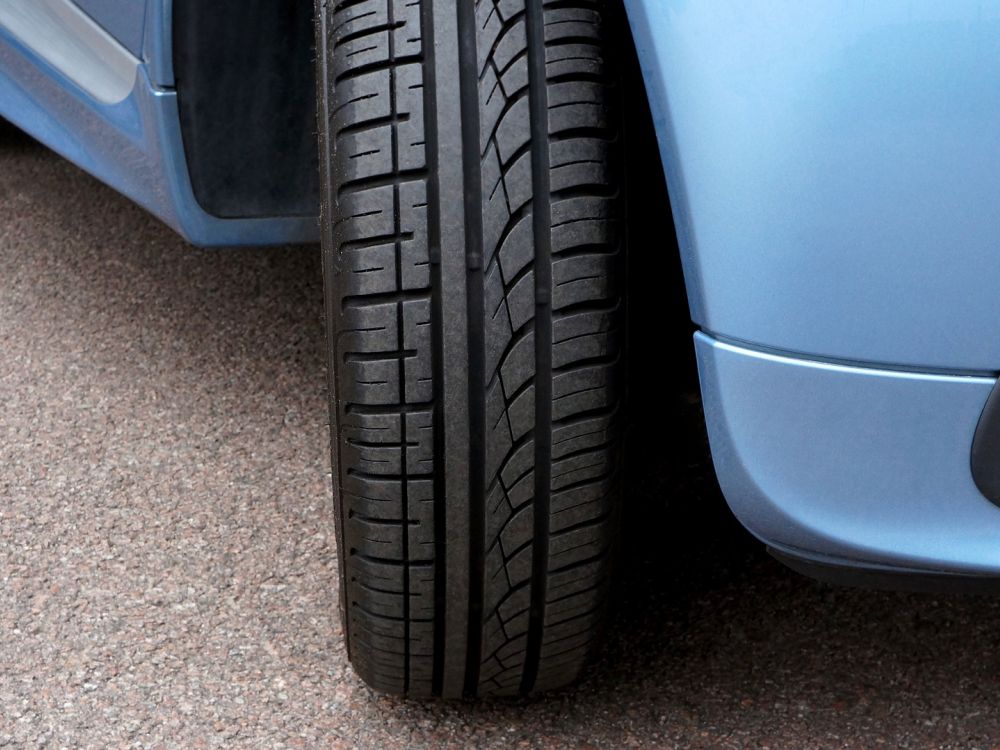 Close up of the front right tyre of a nondescript blue car