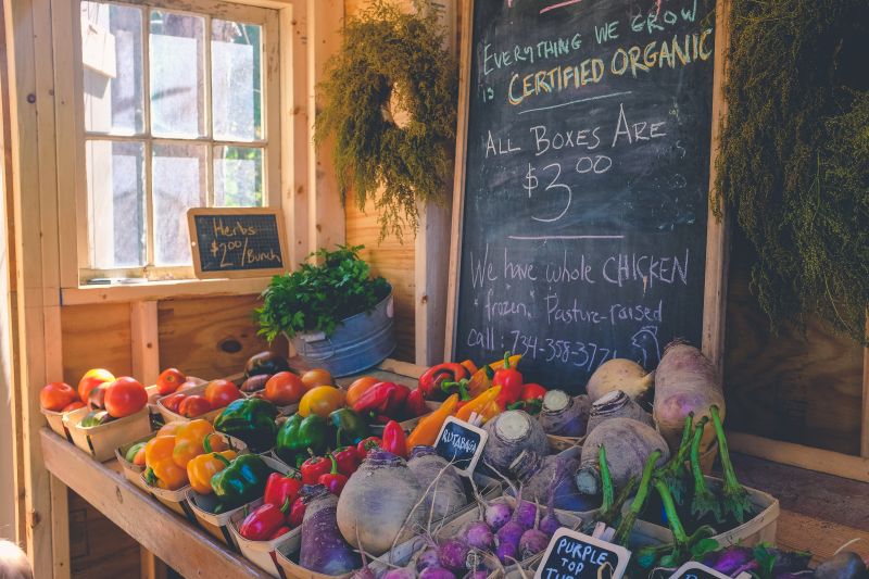 A stall of fresh fruit and vegetables with a sign saying they are certified organic