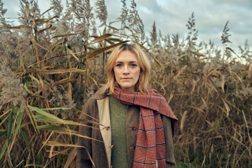 Charlotte Ritchie stands among a sea of tall grasses