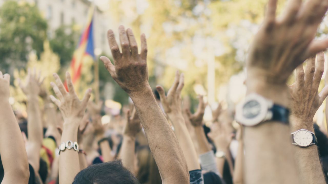 Crowd of people outside raise their hands