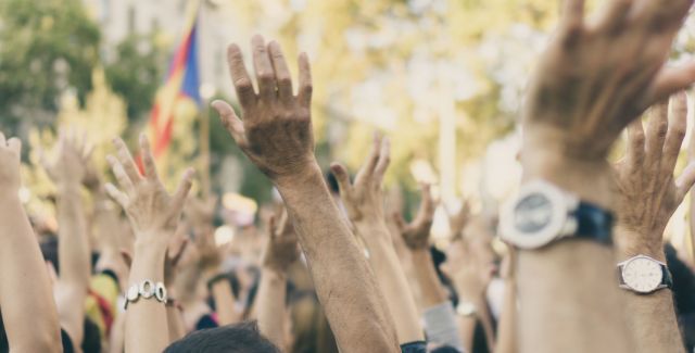 Crowd of people outside raise their hands