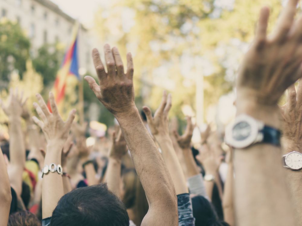 Crowd of people outside raise their hands