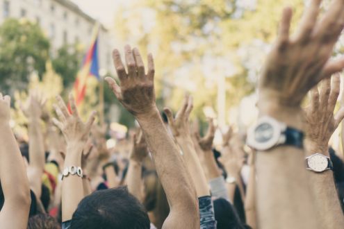 Crowd of people outside raise their hands