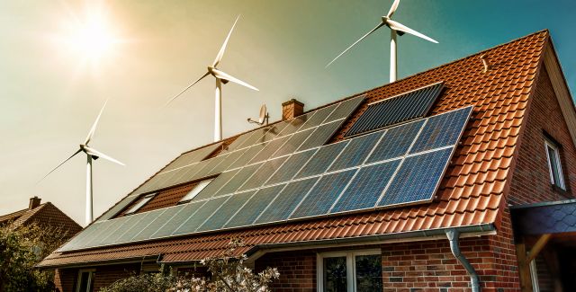 solar panels on bungalow and wind turbines behind bungalow
