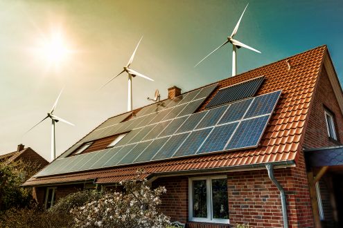 solar panels on bungalow and wind turbines behind bungalow