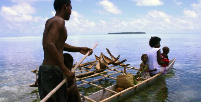A narrow long wooden boat transporting people in Papa New Guinea