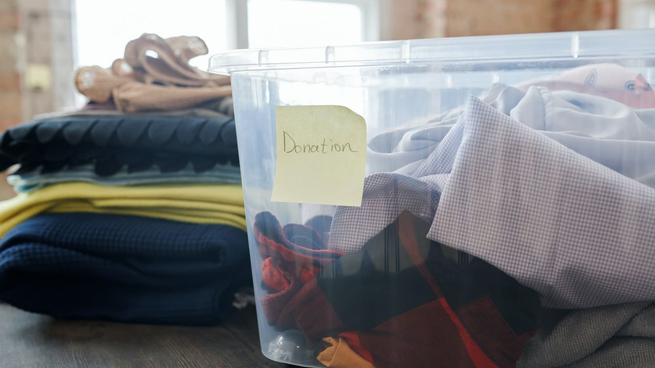 Piles of clothes, some in a box labelled "Donation"
