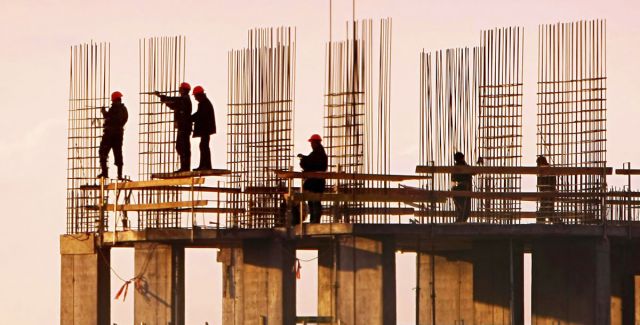 Building construction site, with workers and scaffolding against sky