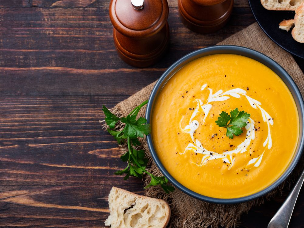 Planet-friendly food: Pumpkin and carrot soup with cream and parsley Top view of pumpkin and carrot soup with cream and parsley