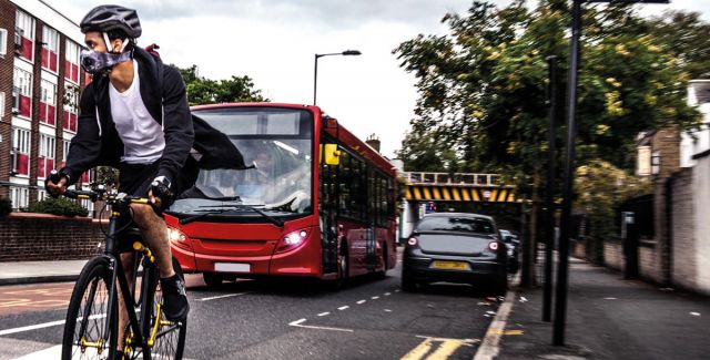 Cyclist wearing breathing mask, on road with bus and cars