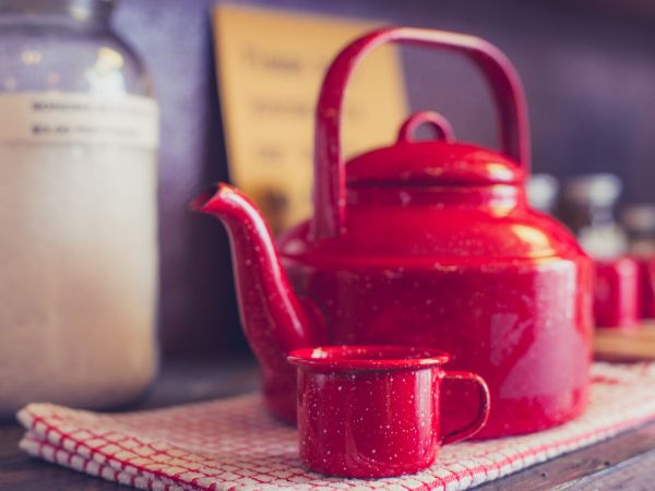 Old red metal kettle with small red metal cup