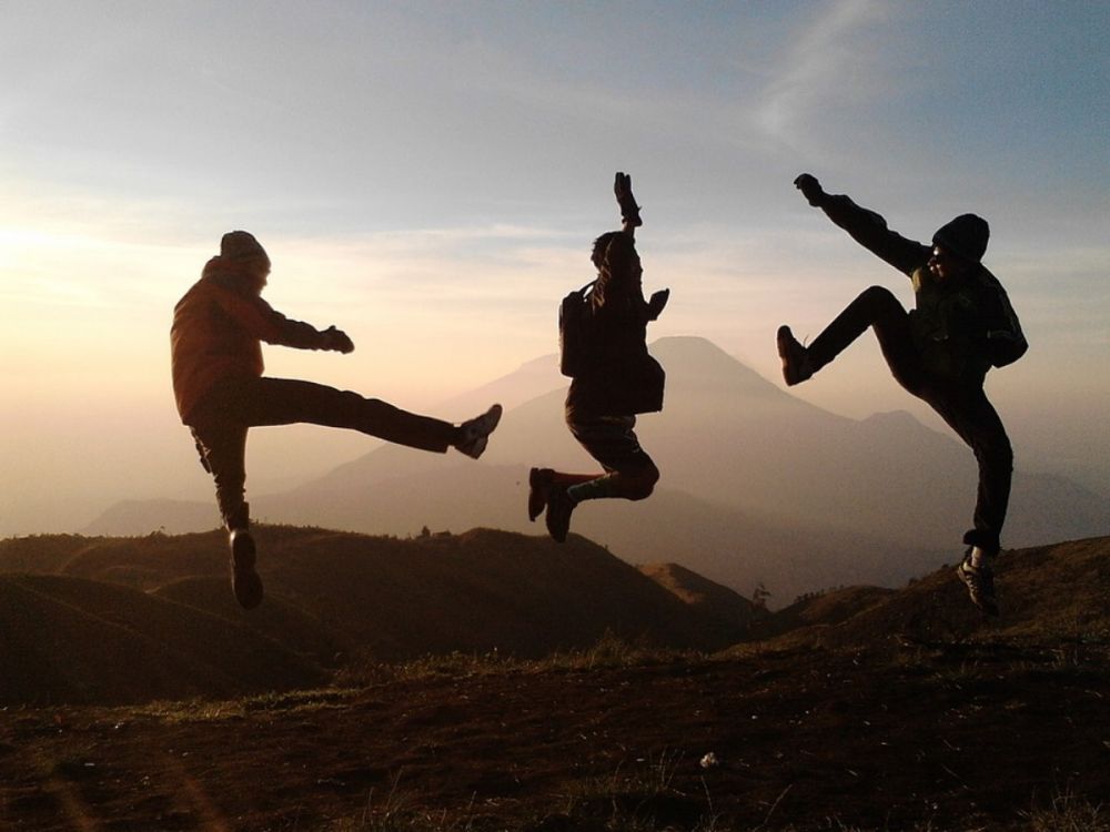 Teenagers jump on a hillside