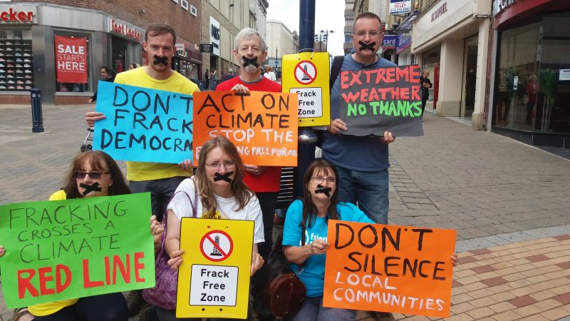 6 Huddersfield Friends of the Earth members in the street with placards protest against permitted developments.