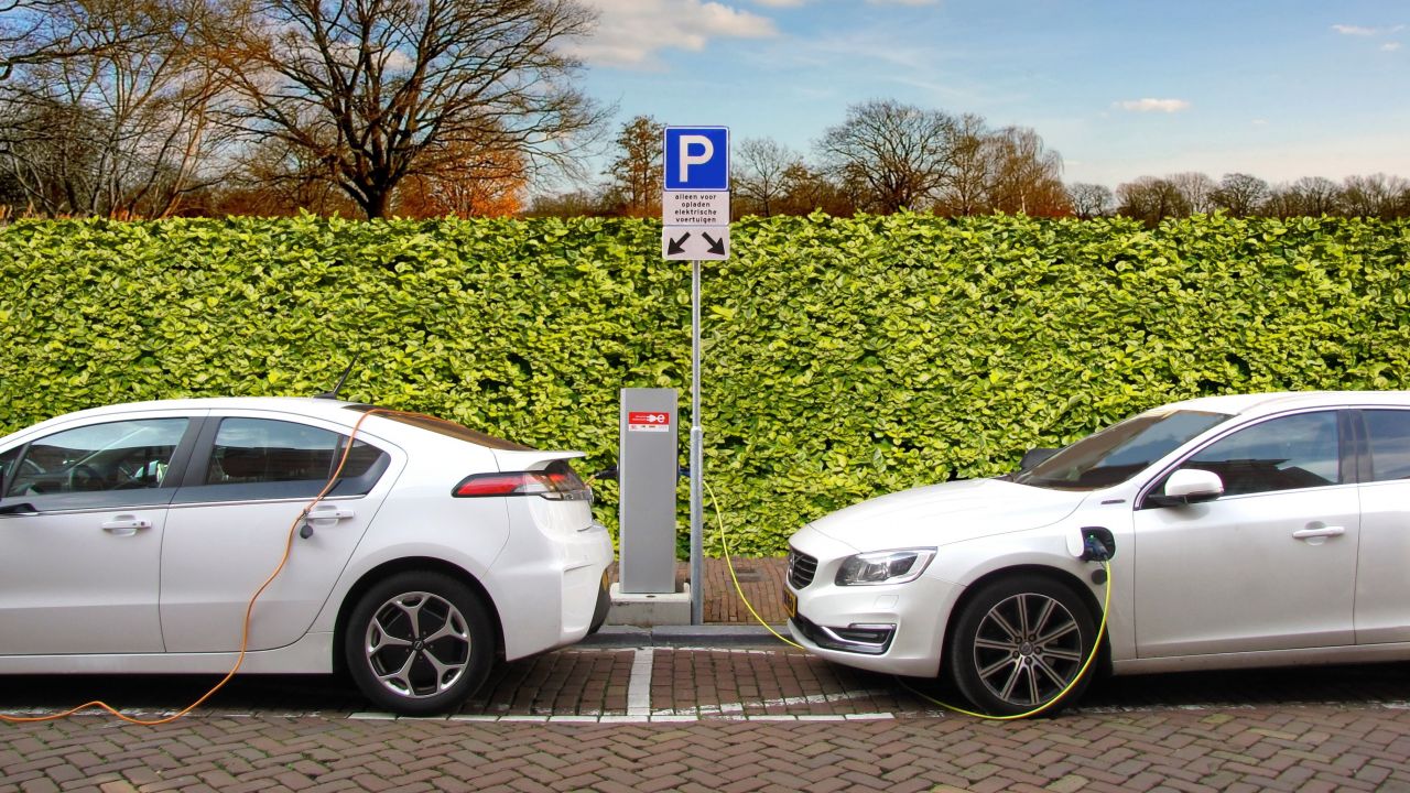 Two white electric cars charging while parked