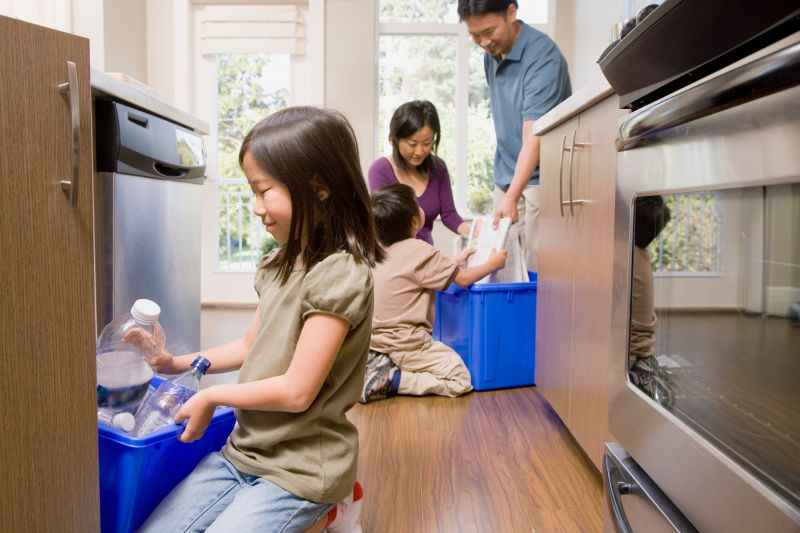 Family in kitchen recycling paper and plastic