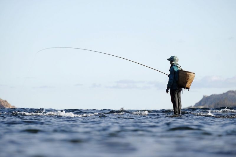 Fisher with fishing rod and basket