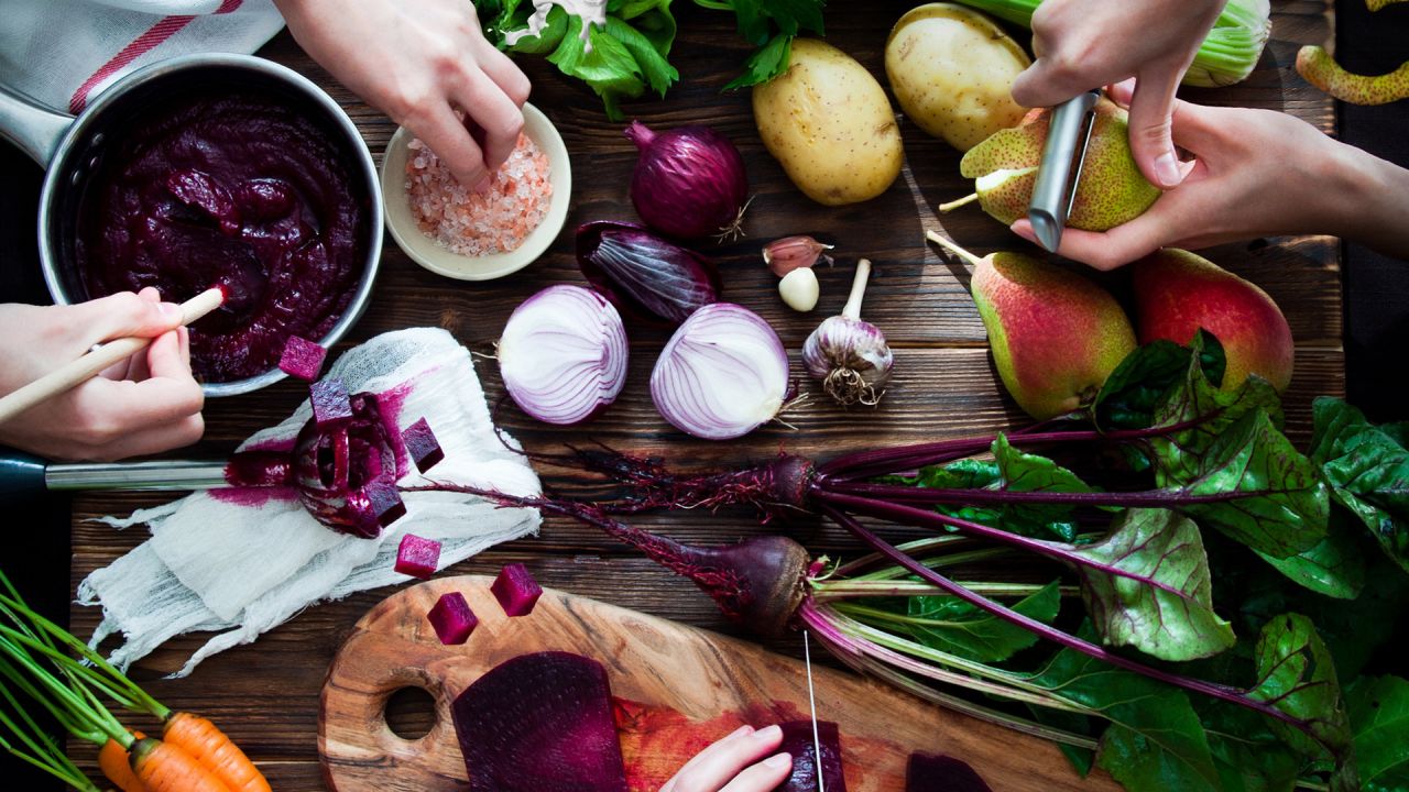 Beetroot, potatoes, onions, pears garlic and carrots on a vibrant chopping board