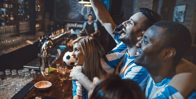 football fans cheering their team on in a bar