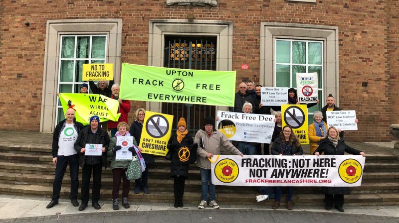 A group photo of about 20 people holding up signs against fracking