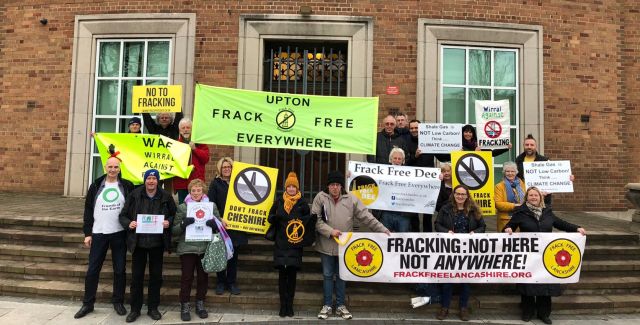 A group photo of about 20 people holding up signs against fracking